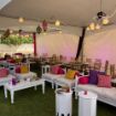 Gentle pink uplighting added via rental LED PAR can lights to a backyard wedding reception tent.