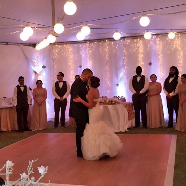 Couple dancing on 12' x 12' rental dance floor under a lighted tent ceiling.