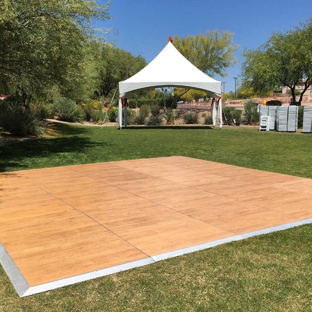 Wood 20' x 21' dance floor setup on the grass with a large tent in the background.