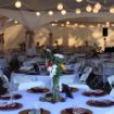 Beautifully decorated wedding tables with flower centerpieces under a Diamond Hexagon Wedding Tent.