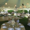Dance floor and globe lighting set over decorated guest tables before a backyard wedding reception.