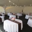 Fully configured wedding reception with decorated guest tables prior to rental chair setup.