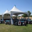 Outdoor wedding using a popular 20' x 40' Wedding Tent Package with guest tables and white resin rental chairs.