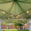 20' x 40' Rectangle wedding tent rental package with globe lights and greenery hung from the canopy cables.