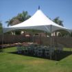 Early setup of a 32 guest backyard tent rental package with 4 round guest tables and 32 white resin chairs.
