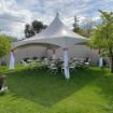 A fully configured backyard tent rental package for 32 guests setup on the back lawn with round guest tables and chairs.