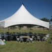 96 Guest backyard tent rental package featuring a hexagon shaped tent, round guest tables, and white plastic chairs.