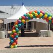 A balloon arch set up in front of a Grand Opening Tent Rental Package before a big ceremony.