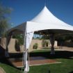 Early setup of a backyard dance tent package with a dance floor and tent leg drapes.