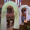 Side picture of multiple wedding arches set up in a church down the center isle.