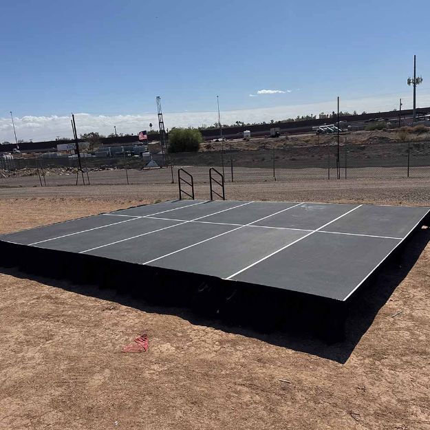 16' x 20' modular event stage with ten 4' x 8' decks connected show from the front on a dirt lot on set up day.